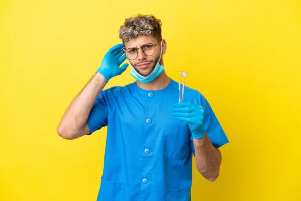 Dentista Caucasiano Homem Segurando Ferramentas Isoladas Fundo Amarelo Com Dúvidas — Fotografia de Stock