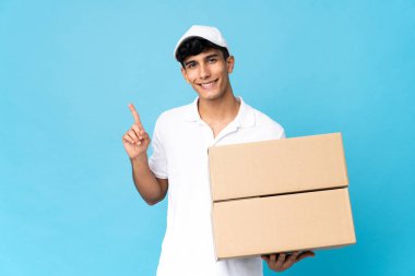Teslimatçı Arjantinli adam mavi arka planda izole edilmiş ve en iyinin işareti olarak parmağını kaldırıyor.