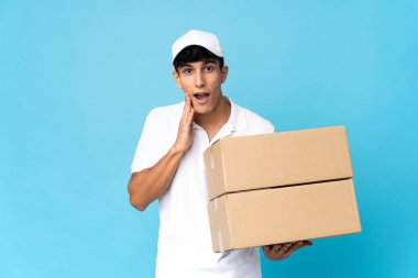 Teslimatçı Arjantinli adam mavi arka planda şaşırmış ve şok olmuş bir yüz ifadesiyle izole edilmiş.