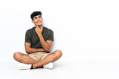 Genç Arjantinli bir adam yerde oturuyor. Kafasını kaldırıp bakarken bir fikir düşünüyor.