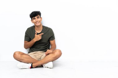 Genç Arjantinli adam yerde oturuyor.