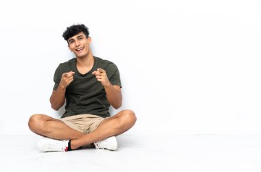 Genç Arjantinli adam yerde oturuyor ve gülümsüyor.