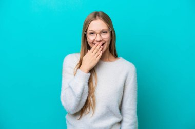 Mavi arka planda izole edilmiş genç Rus kadın mutlu ve gülümsüyor.