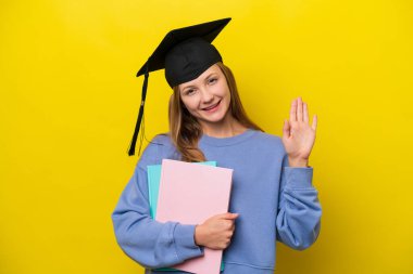 Genç Rus öğrenci, sarı arka planda izole edilmiş, mutlu bir ifadeyle selamlanıyor.