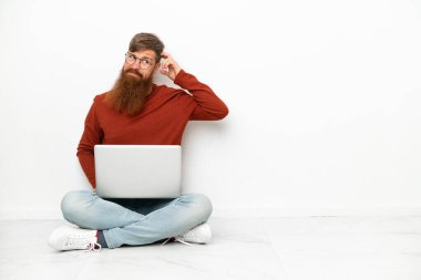 Dizüstü bilgisayarı beyaz arka planda izole edilmiş genç, beyaz bir adam. Şüpheleri var.