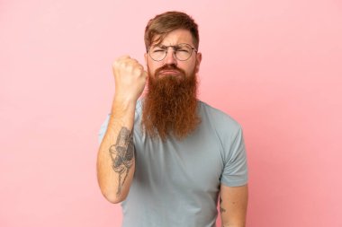 Kırmızımsı beyaz adam mutsuz bir ifadeyle pembe arka planda izole edilmiş.