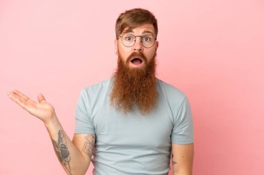 Pembe arka planda izole edilmiş genç beyaz adam şüpheli hareketler yapıyor.