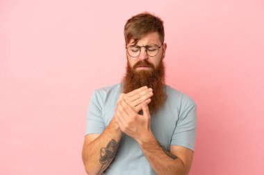 Kırmızımsı beyaz adam pembe arka planda izole edilmiş ellerinde acıdan muzdarip