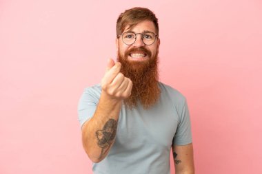 Pembe arka planda izole edilmiş genç beyaz adam para hareketi yapıyor.