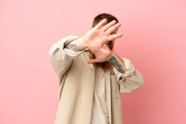 Pembe arka planda izole edilmiş genç, beyaz adam gergin eller öne doğru uzanıyor.