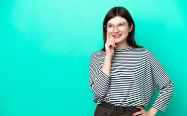 Genç Rus kadın yeşil arka planda izole edilmiş bir şekilde yukarı bakarken bir fikir düşünüyor.