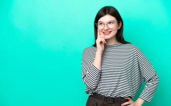 Genç Rus kadın yeşil arka planda izole edilmiş bir şekilde yukarı bakarken bir fikir düşünüyor.