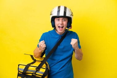 Sırt çantalı genç Brezilyalı adam sarı arka planda izole edilmiş ve galibiyeti kutluyor.