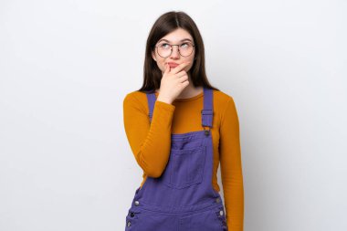 Mavi arka planda izole edilmiş genç bir Rus kadının şüpheleri ve kafa karıştırıcı bir yüz ifadesi var.