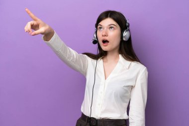 Mor arka planda izole edilmiş bir kulaklıkla çalışan pazarlamacı Rus kadın.