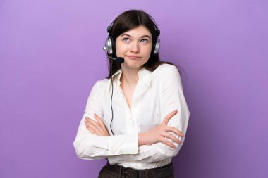 Mor arka planda izole edilmiş bir kulaklıkla çalışan pazarlamacı Rus kadın omuzlarını kaldırırken şüpheli hareketlerde bulunuyor.