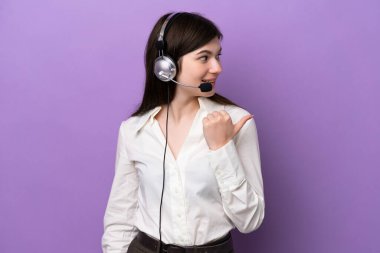 Mor arka planda izole edilmiş bir kulaklıkla çalışan pazarlamacı Rus kadın bir ürünü sunmak için kenarı işaret ediyor.