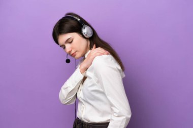 Kulaklıkla çalışan pazarlamacı Rus kadın, mor arka planda izole edilmiş, omuz ağrısı çeken, çaba sarf ettiği için...