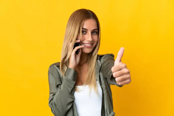 Young Blonde Woman Isolated Yellow Background Keeping Conversation Mobile While — Stock Photo, Image