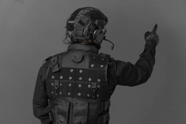 Özel Tim 'in beyaz adamı gri arka planda izole edilmiş. İşaret parmağıyla işaret ediyor.