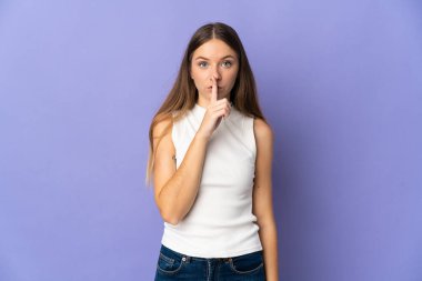 Mor arka planda izole edilmiş genç Litvanyalı kadın parmağını ağzına koyan sessiz bir jest işareti gösteriyor.