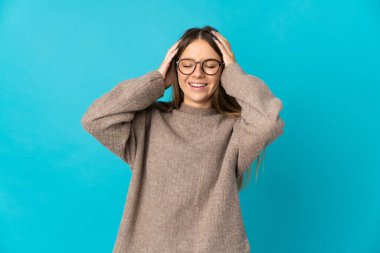 Genç Litvanyalı kadın mavi arka planda izole edilmiş gülüyor.