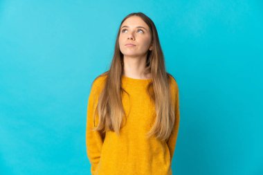 Genç Litvanyalı kadın mavi arka planda izole edilmiş ve yukarı bakıyor.