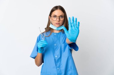 Litvanyalı kadın diş hekimi, arka planda izole edilmiş aletler tutuyor.