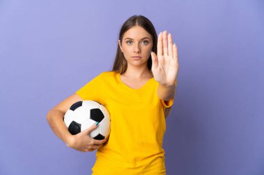 Litvanyalı genç futbolcu kadın, mor arka planda izole edilmiş, dur hareketi yapıyor.