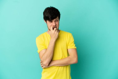 Genç Rus adam mavi arka planda izole edilmiş gergin ve korkmuş.