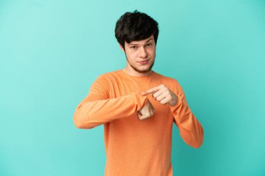 Genç Rus adam mavi arka planda izole edilmiş, geç kalma hareketi yapıyor.