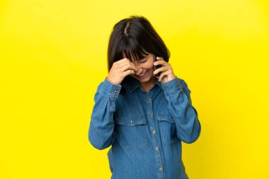 Sarı arka planda izole edilmiş cep telefonu kullanan hamile kadın gülüyor.