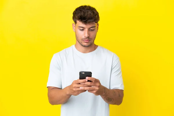 Sarı Arka Planda Cep Telefonuyla Izole Edilmiş Beyaz Yakışıklı Bir — Stok fotoğraf