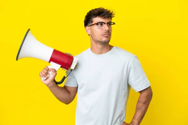 Young Caucasian Handsome Man Isolated Yellow Background Holding Megaphone Thinking — Fotografia de Stock