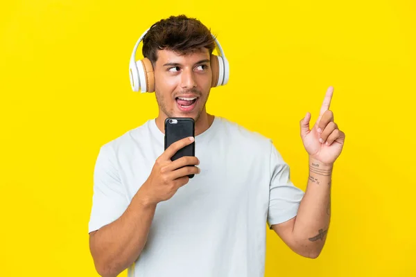 Jeune Homme Beau Caucasien Isolé Sur Fond Jaune Écoutant Musique — Photo