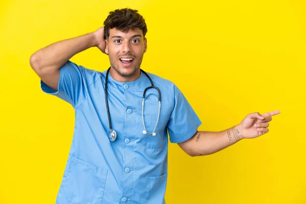 Mladý Chirurg Lékař Muž Izolované Žlutém Pozadí Překvapen Ukazuje Prstem — Stock fotografie