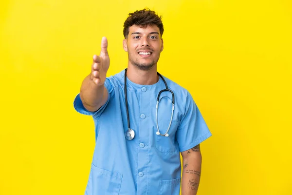 Νεαρός Χειρουργός Γιατρός Απομονωμένος Στο Κίτρινο Φόντο Σφίγγει Χέρια Για — Φωτογραφία Αρχείου
