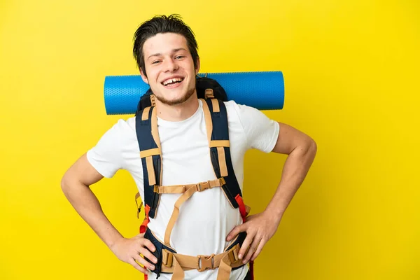 年轻的登山运动员 俄罗斯男子 背着一个大背包 黄色背景 双手叉腰 面带微笑 — 图库照片