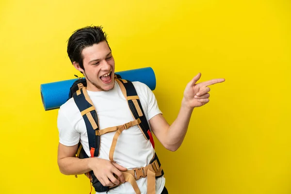 Young Mountaineer Russian Man Big Backpack Isolated Yellow Background Pointing — Stockfoto