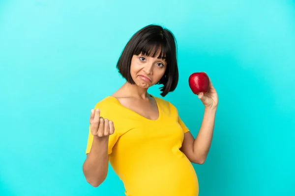 妊娠中の女性を保持していますリンゴ隔離上の青の背景作りお金ジェスチャー — ストック写真