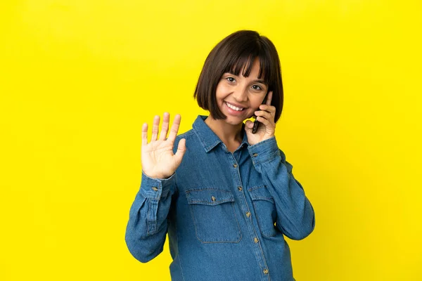 Mujer Embarazada Usando Teléfono Móvil Aislado Sobre Fondo Amarillo Saludando —  Fotos de Stock