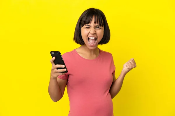 Young Mixed Race Pregnant Woman Isolated Yellow Background Using Mobile — Stock Photo, Image