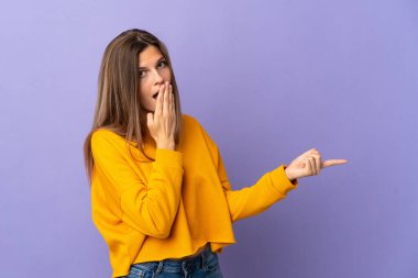 Genç Slovak kadın mor arka planda izole edilmiş sürpriz bir ifadeyle işaret ederken