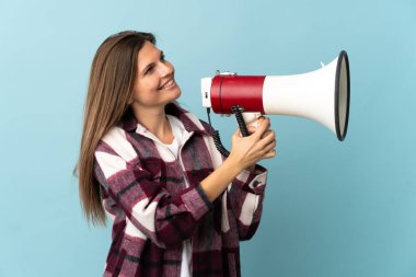 Genç Slovak kadın mavi arka planda izole edilmiş megafonla bir şey duyurmak için bağırıyor.