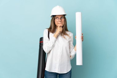 Slovak mimar kızın elinde mavi arka planda izole edilmiş planlar var. Şüpheleri ve düşünceleri var.
