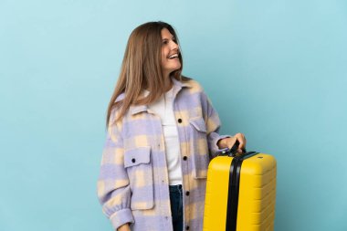 Genç Slovak kadın mavi arka planda izole edilmiş seyahat valiziyle tatilde.