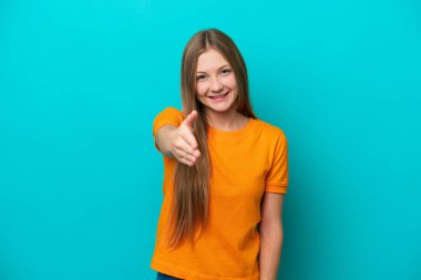 Mavi arka planda izole edilmiş genç bir Rus kadın iyi bir anlaşma için el sıkışıyor.