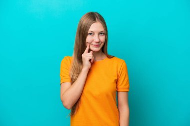 Genç Rus kadın mavi arka planda izole edilmiş ve düşünüyor