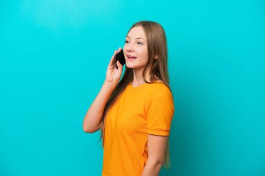 Genç Rus kadın mavi arka planda izole edilmiş cep telefonuyla sohbet ediyor.