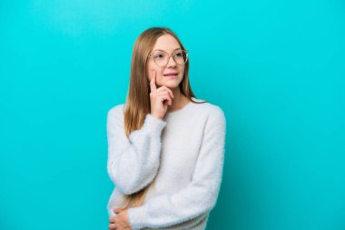 Genç Rus kadın mavi arka planda izole edilmiş bir şekilde yukarı bakarken bir fikir düşünüyor.